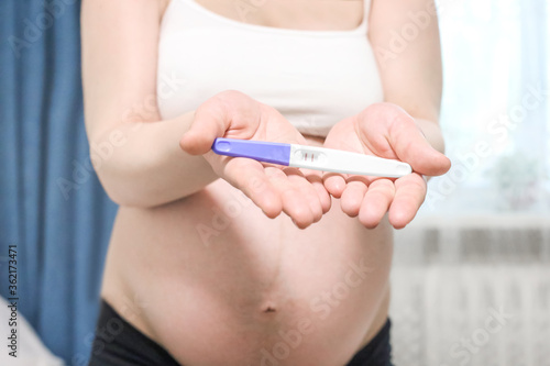 Happy pregnant woman holding pregnancy test with beautiful belly that pregnant girl has fetus inside. Young Mother waiting newborn baby prenatal  pregnancy  motherhood  expecting concept