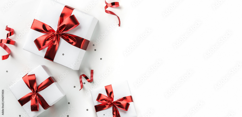 White holiday gift boxes with red ribbon, sparkles, confetti on white background. Happy Birthday, Valentines day, Women's day, Merry Christmas card. Flat lay, top view, wide composition White holiday gift boxes with red ribbon, sparkles, confetti on white background. Happy Birthday, Valentines day, Women's day, Merry Christmas card. Flat lay, top view, wide composition