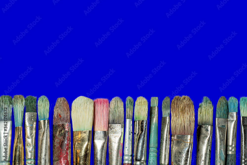 old oil paint brushes isolated at the bottom of a marine blue background