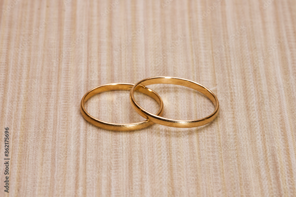 two golden wedding rings on wooden background two golden wedding rings on wooden background