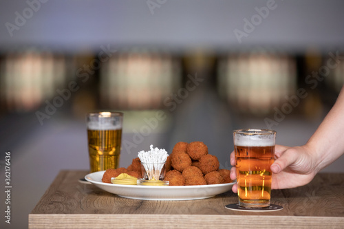 Bitterballen with mustard at a bowling alley with a beer that is being grabbed