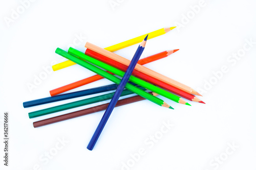 Lot of different colored wood pencil crayons scattered across a white paper