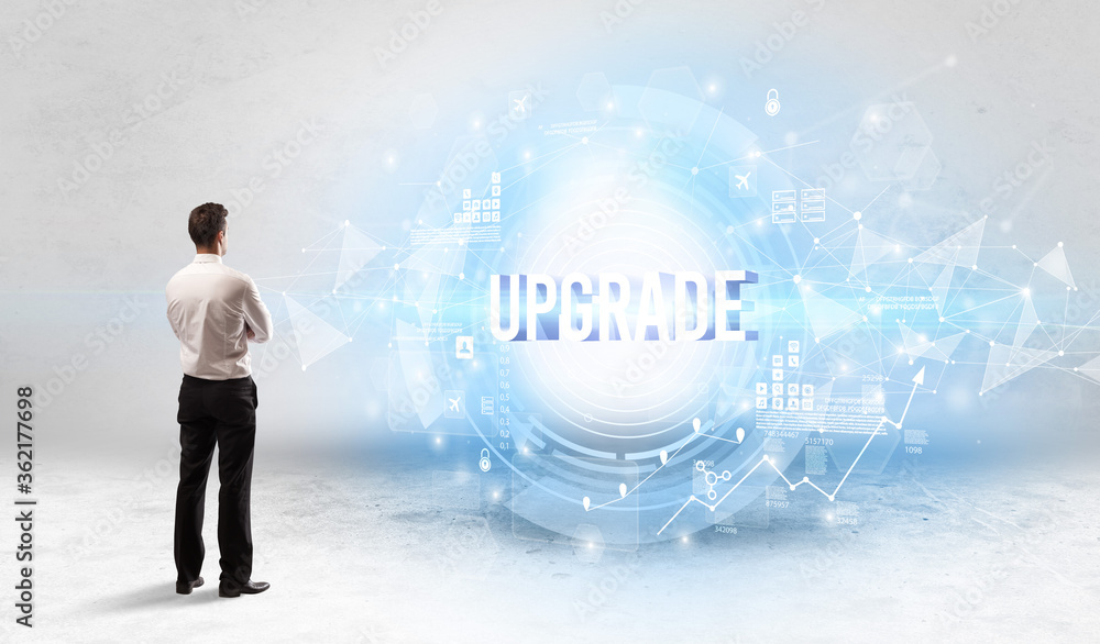 Rear view of a businessman standing in front of UPGRADE inscription, modern technology concept Rear view of a businessman standing in front of UPGRADE inscription, modern technology concept