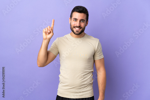 Young handsome man with beard over isolated background pointing up a great idea