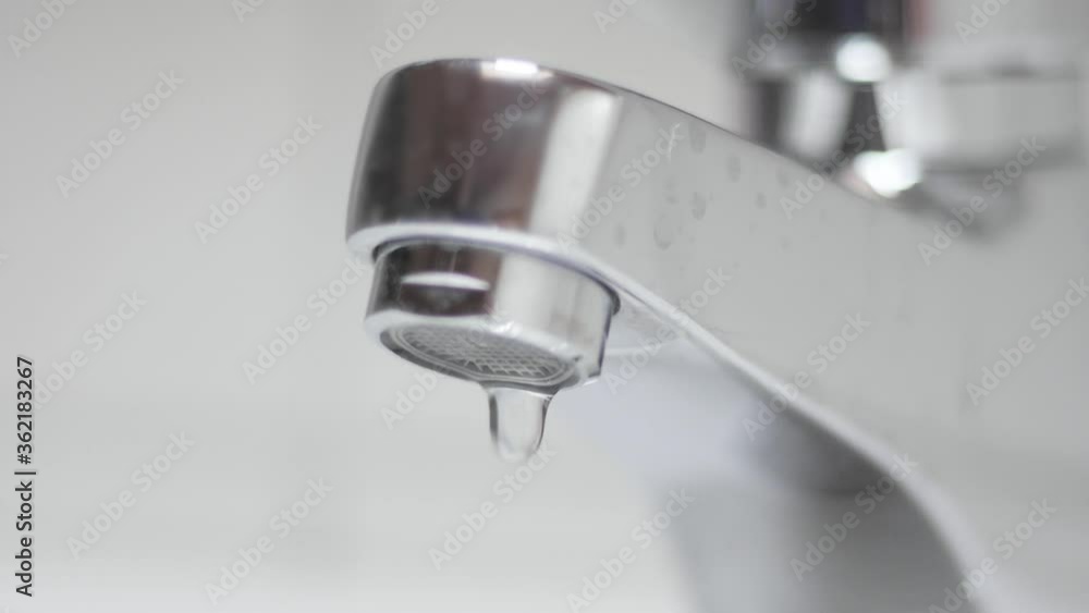 Closeup of water dripping from a bathroom or kitchen faucet. Seen in slow motion. Water supply, drought, sanitation concept. Closeup of water dripping from a bathroom or kitchen faucet. Seen in slow motion. Water supply, drought, sanitation concept.