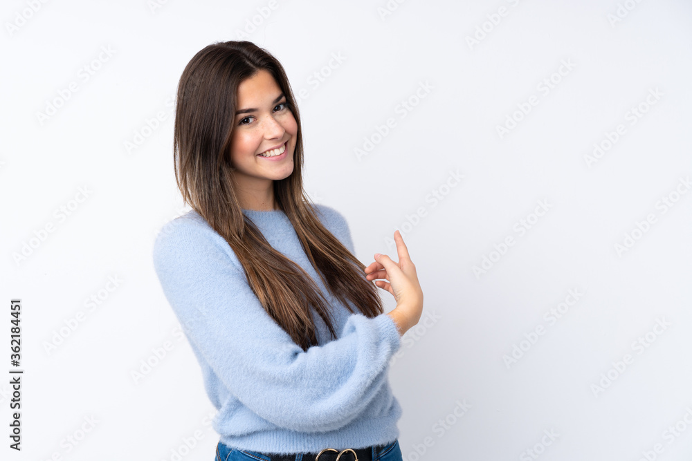 Teenager girl over isolated white background pointing back Teenager girl over isolated white background pointing back