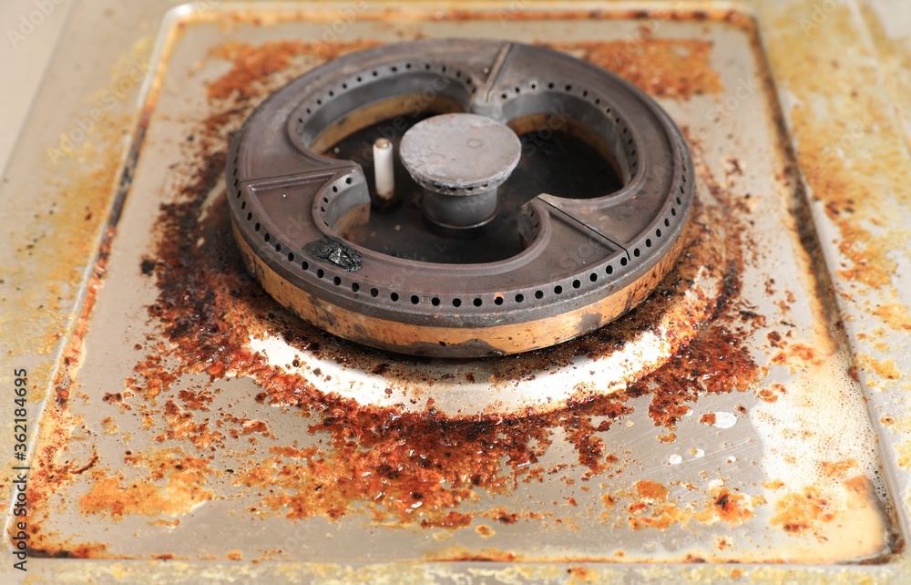 Dirty modern gas stove with cooking oil stains and burned food remnants on surface Dirty modern gas stove with cooking oil stains and burned food remnants on surface