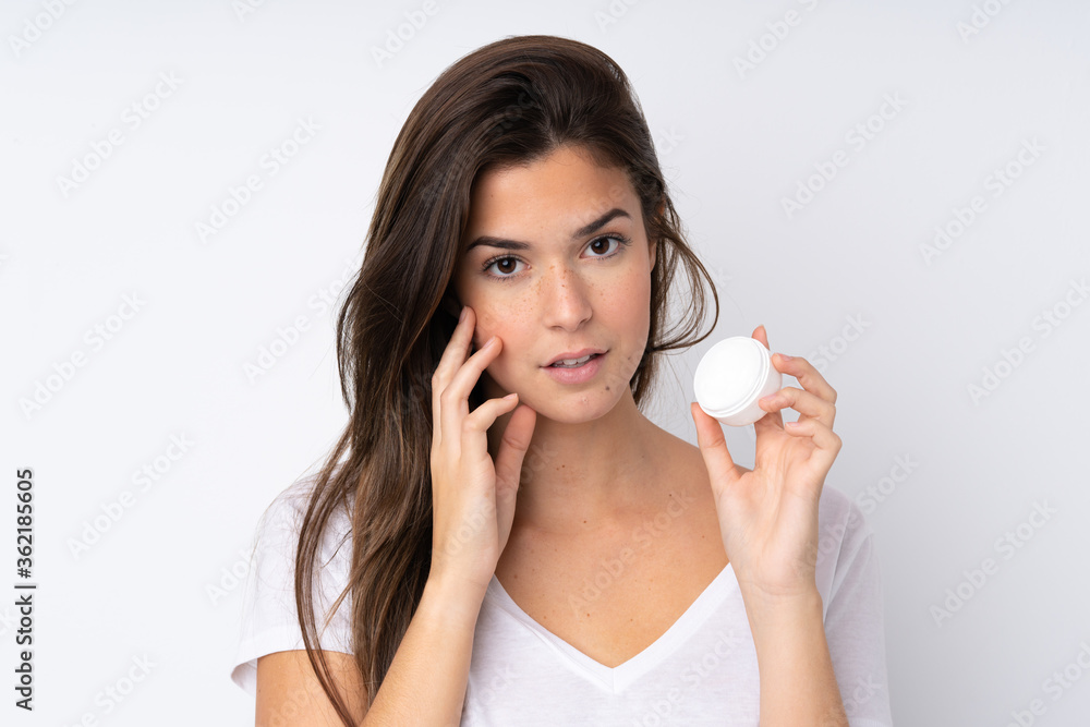 Teenager girl over isolated background with moisturizer Teenager girl over isolated background with moisturizer