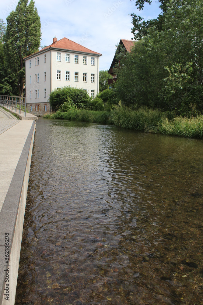 Transparent water of the river Gera running through Erfurt, in Germany, and reflecting a German house. 