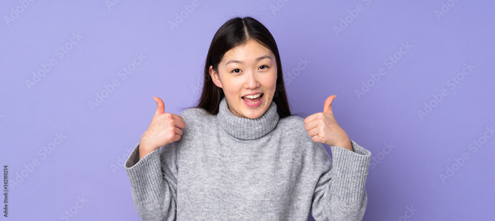 Young asian woman over isolated background giving a thumbs up gesture - obrazy, fototapety, plakaty 