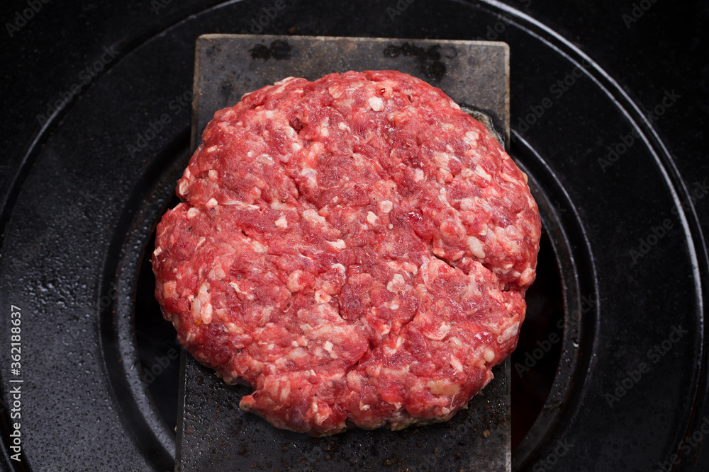 Burger meat cooking on top of hot volcanic stone