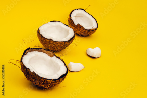 Parts of coconut on a colored background. Close up. Fresh ripe coconut broken into pieces.