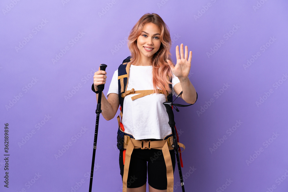 Teenager girl with backpack and trekking poles over isolated purple background counting five with fingers Teenager girl with backpack and trekking poles over isolated purple background counting five with fingers