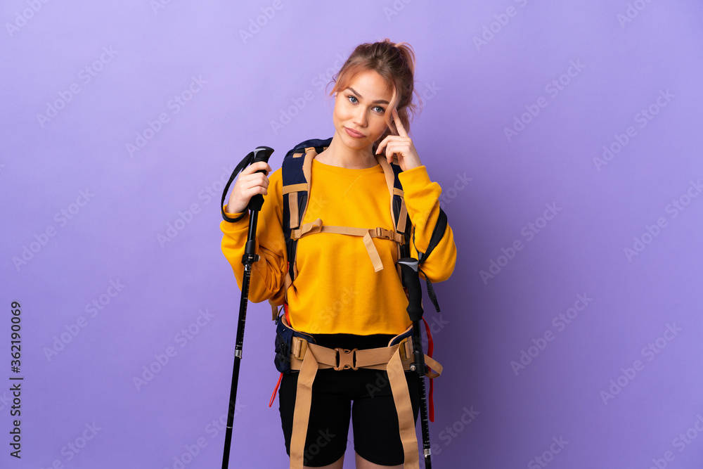 Teenager girl with backpack and trekking poles over isolated purple background thinking an idea Teenager girl with backpack and trekking poles over isolated purple background thinking an idea