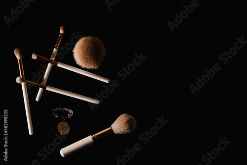 Elegantly lit make-up brushes on a black background