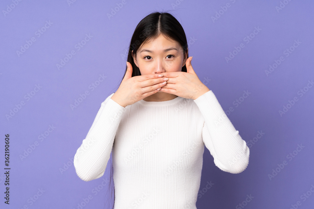 Young asian woman isolated on purple background covering mouth with hands Young asian woman isolated on purple background covering mouth with hands