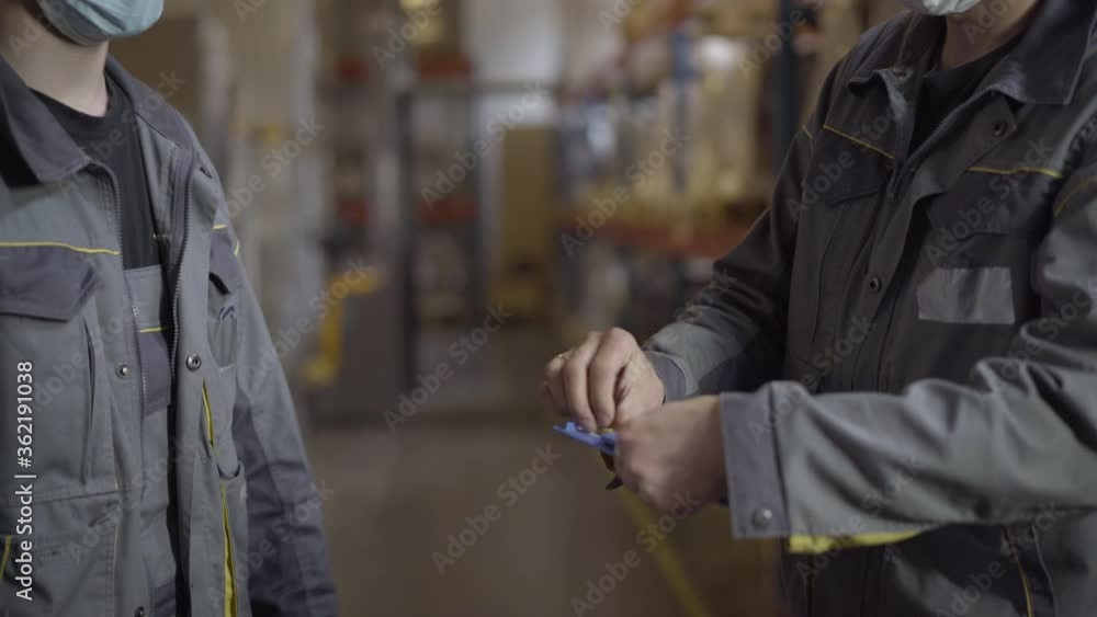Unrecognizable men in face masks shaking hands after signing transportation documents. Caucasian male employees passing bill of landing and leaving. Coronavirus logistics. Unrecognizable men in face masks shaking hands after signing transportation documents. Caucasian male employees passing bill of landing and leaving. Coronavirus logistics.