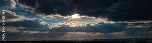 Foto Panorama d'un couché de soleil perçant à travers les nuages avec ses rayons en p