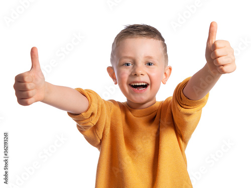 Portrait of a beautiful European boy 6 years old on a white background. The child spreads his hands to the sides and shows the class. Children's emotions.