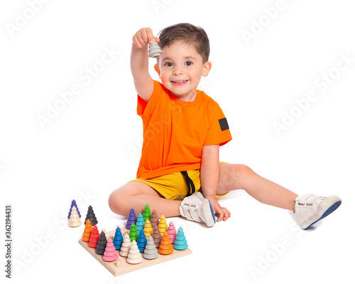 A beautiful European boy plays with wooden Montessori toys on a white background. Child 2.5 years old. Montessori pedagogy, didactic materials. Development and training of preschool children.