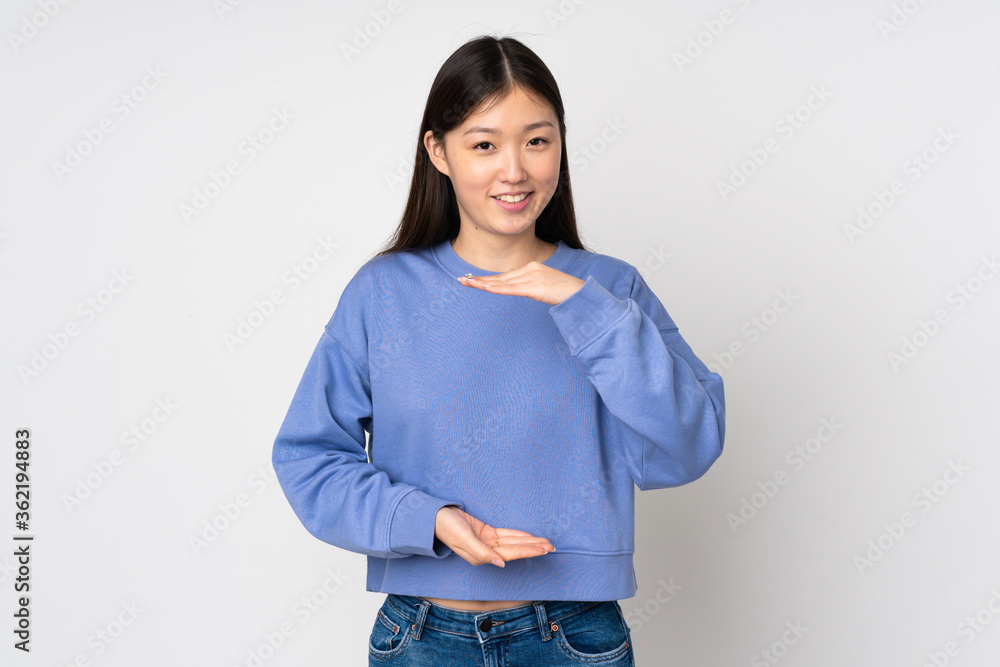Young asian woman isolated on background holding copyspace imaginary on the palm to insert an ad Young asian woman isolated on background holding copyspace imaginary on the palm to insert an ad