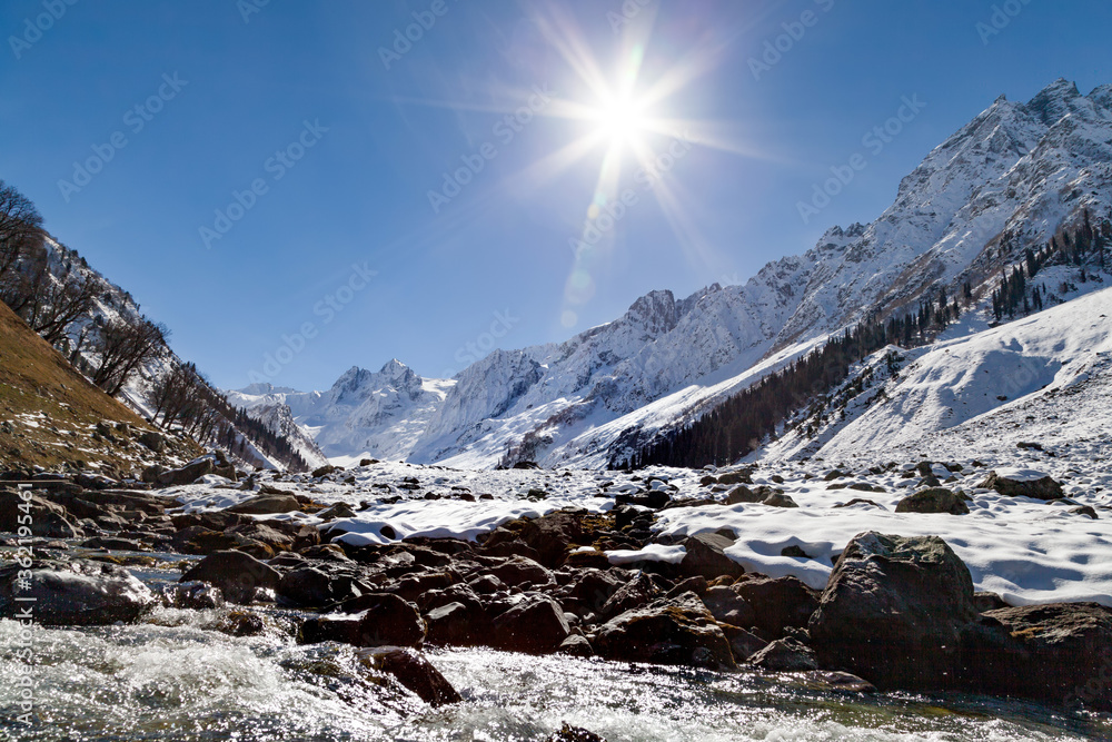 Sun Shines over a water stream created by melting snow down the