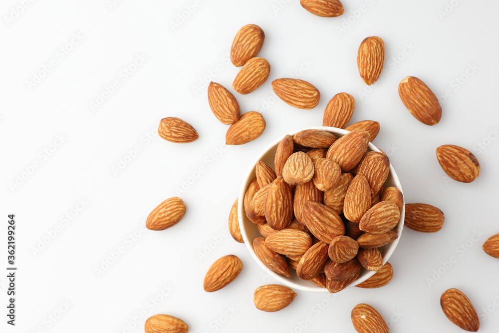 Almonds nut seed in white bowl flat lay top view heap on white background with copy space on the left. Snack whole healthy food is useful to help neutralize free radicals and provide energy. Almonds nut seed in white bowl flat lay top view heap on white background with copy space on the left. Snack whole healthy food is useful to help neutralize free radicals and provide energy.