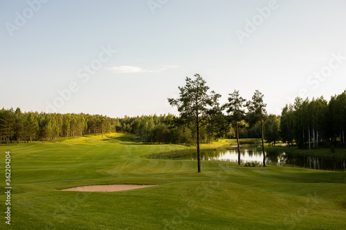 The photo shows a golf course, green grass and trees.