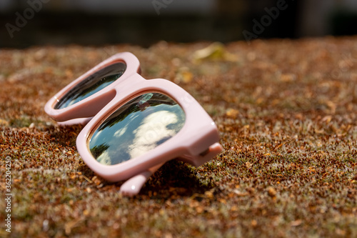 Pair of pink sunglasses lying on the ground