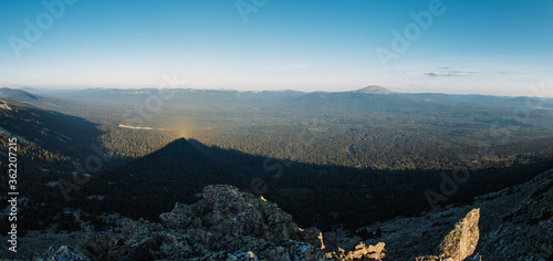 the shadow of the mountain lies on the forest
