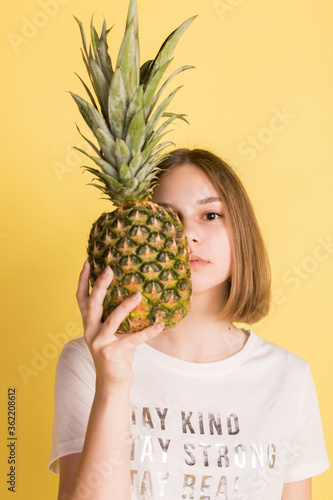 Girl with pineapple on yellow background
