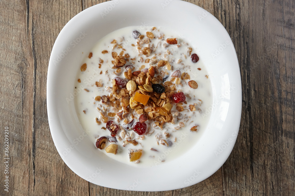 Granola (muesli) for breakfast with oatmeal, various seeds and dried fruits in a white plate with milk. Healthy and delicious diet breakfast. Granola (muesli) for breakfast with oatmeal, various seeds and dried fruits in a white plate with milk. Healthy and delicious diet breakfast.