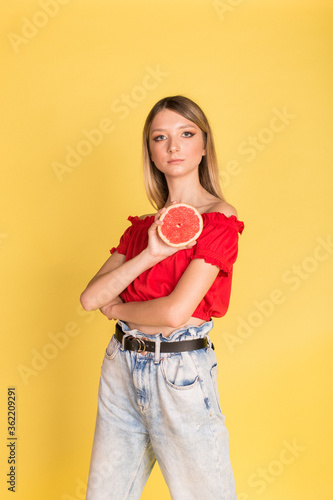 Beautiful young caucasian beauty girl portrait on yellow background with grapefruit