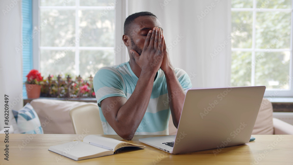 Frustrated afro-american guy sitting at his desk closing eyes massaging nose thinking on difficult task. Frustrated afro-american guy sitting at his desk closing eyes massaging nose thinking on difficult task.