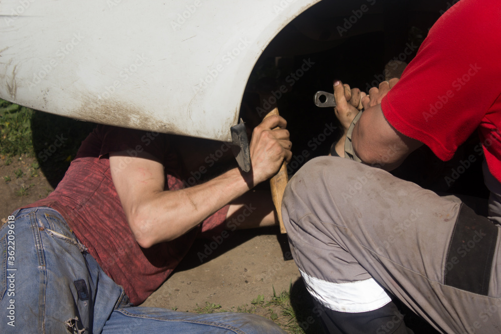 Two auto mechanics examining car. Repair the car wheel.