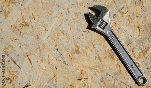 Repair tool. Silver adjustable wrench on a wooden surface background, free space for text, top view