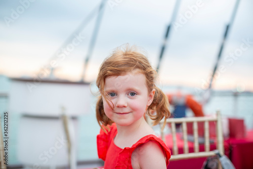Red head girl in a red romper on a boat