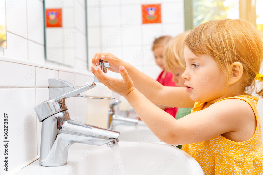 Child in kindergarten washing her hands - obrazy, fototapety, plakaty 