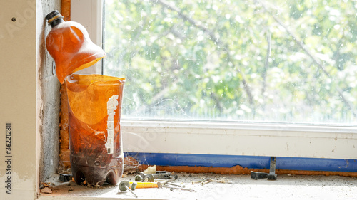 A mess in front of a window, a plastic bottle with a cut neck