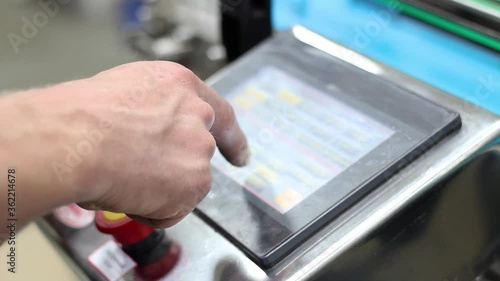 Worker's hand at the factory leads a finger on a metal device with a touch monitor. Close-up. High quality FullHD footage