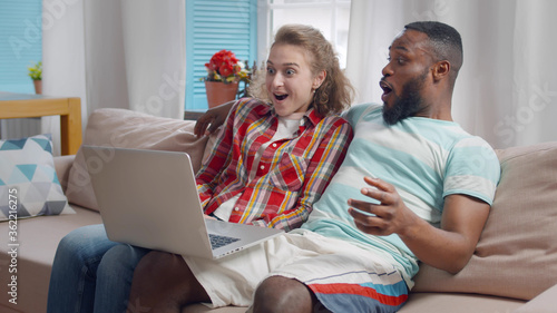 Fotografi Young man and woman in love watching comedy show on laptop in living room