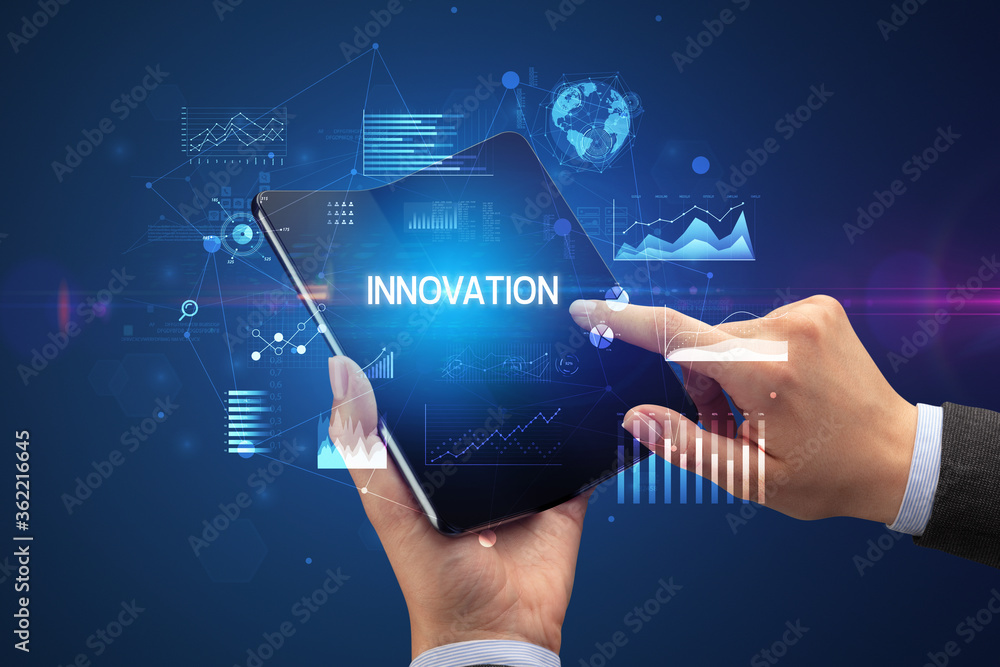 Businessman holding a foldable smartphone with INNOVATION inscription, successful business concept