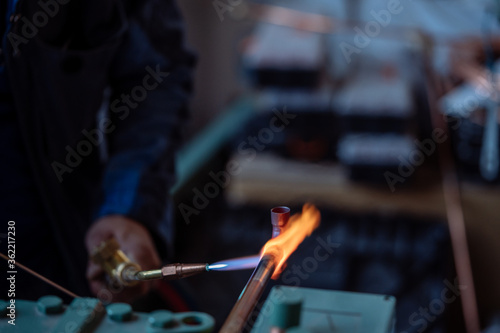 Foto Flame of a copper welding machine heats a copper pipe in a workshop