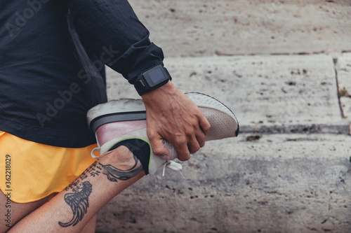 Dettaglio scarpa di un giovane atleta sportivo durante esercizio di stretching per una sessione di corsa urbana