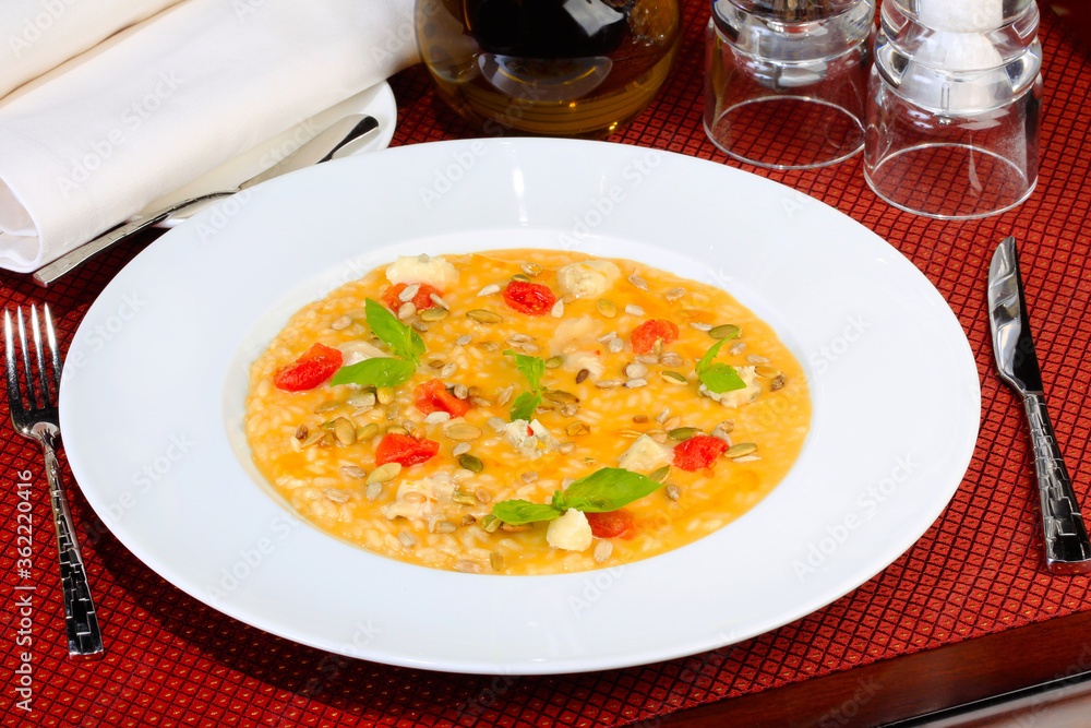 Rice with pumpkin seeds, tomatoes and cereals with sauce in white plate, cutlery. As backdrop for menus, cookbooks, advertisements and other culinary projects
