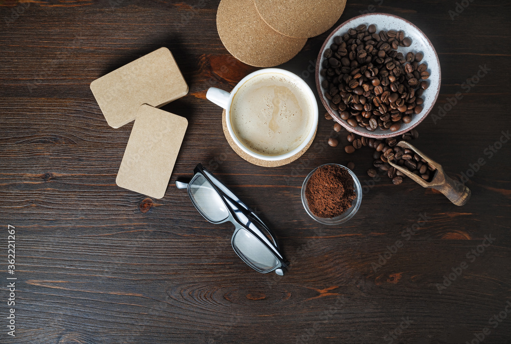 Coffee cup, kraft business cards, roasted coffee beans, glasses and coffee ground on wood table background. Flat lay. Coffee cup, kraft business cards, roasted coffee beans, glasses and coffee ground on wood table background. Flat lay.