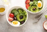 Salad bowl with avocado, spinach, egg, tomatoes and olives. Flat layot