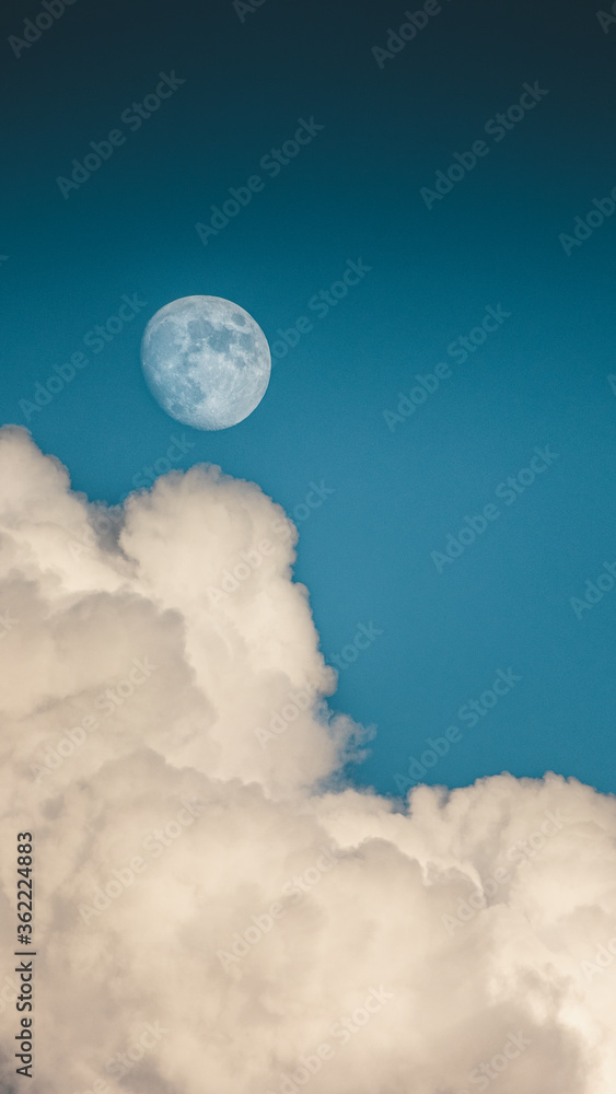 Evening sky with clouds and bright partial moon. Nightsky with large moon, nature background. Vertical photo.
