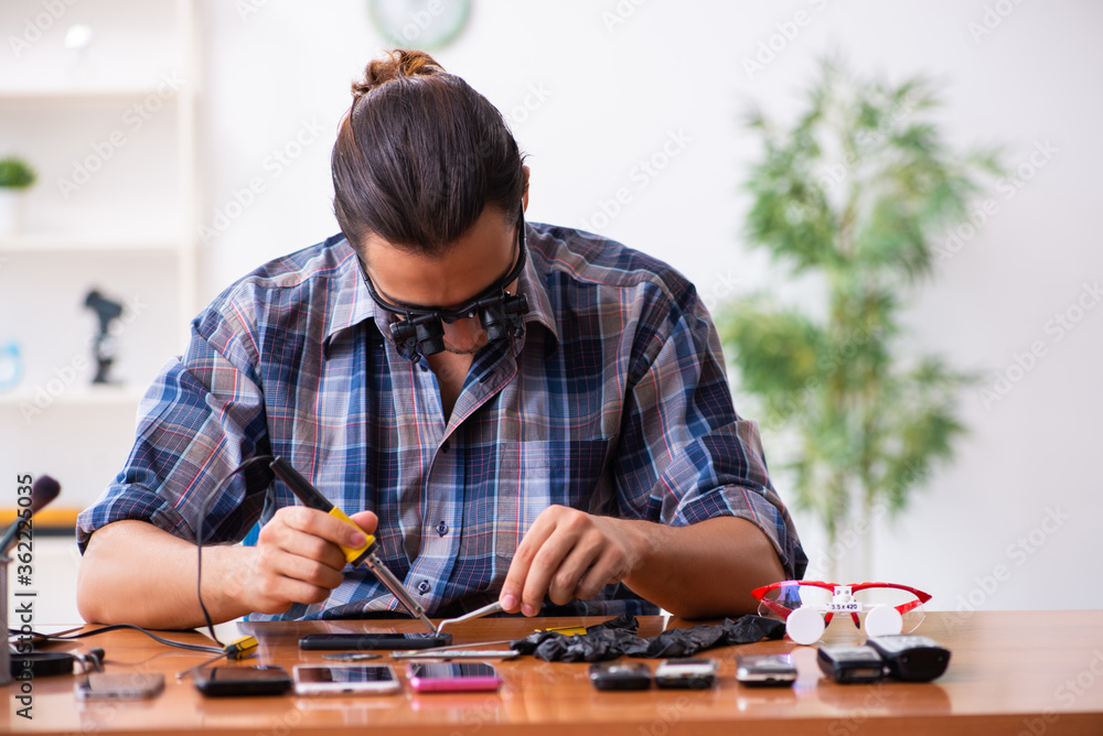 Fototapeta premium Young male technician repairing mobile phone