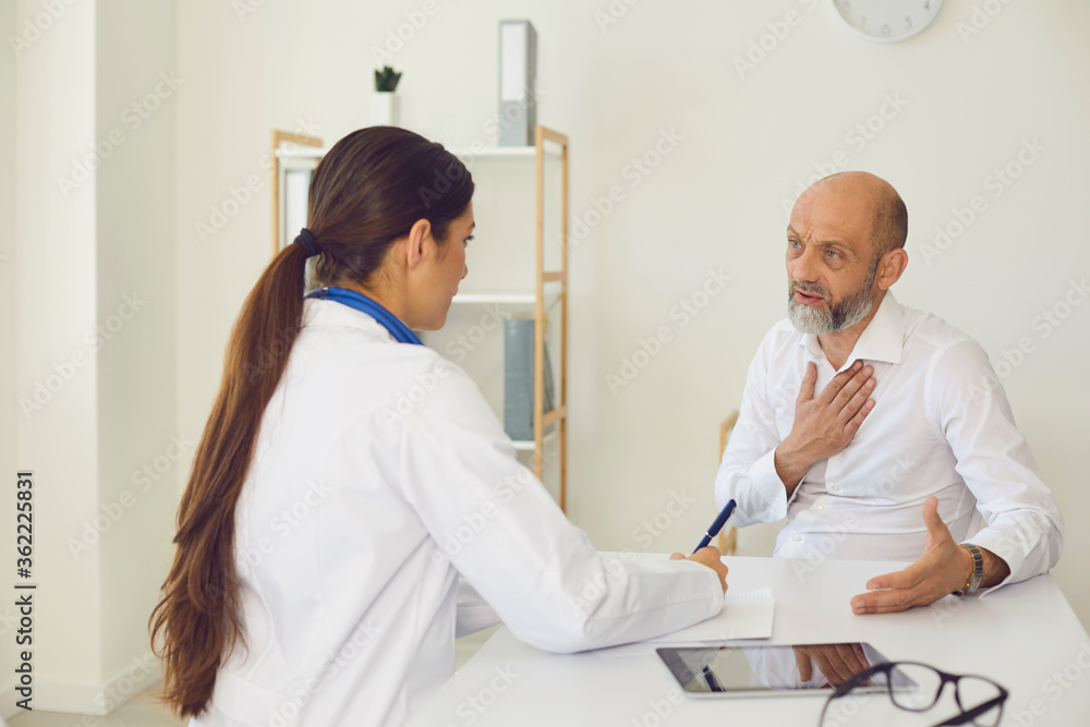 Fototapeta premium Worried senior patient consulting doctor at clinic. Elderly man on visit to his physician at hospital